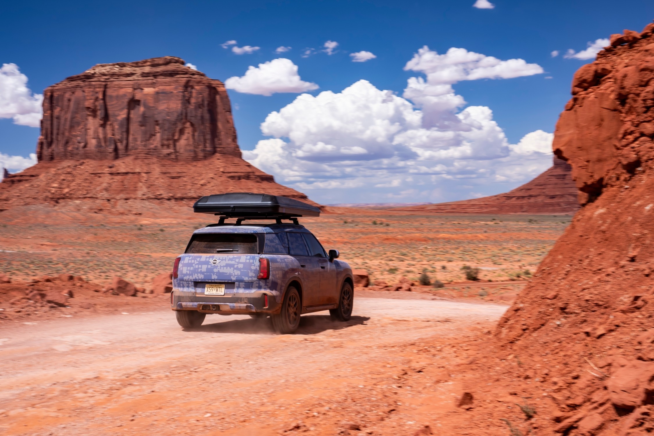 MINI Countryman visto pela traseira, a circular numa estrada de terra batida, rodeado  por formações rochosas no deserto 